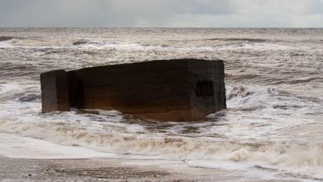 Wellen-Brechen-über-Der-Spitze-Eines-Säulenkastens-Aus-Dem-Zweiten-Weltkrieg-Am-Strand-Von-Hemsby