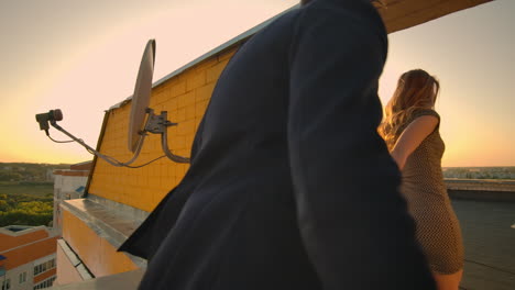 young couple holding hands walking woman leading boyfriend the roof of the building at sunset pov travel concept. carefree free lovers run on the roof laughing and smiling