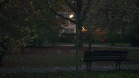 park bench behind a chain-link fence at dusk