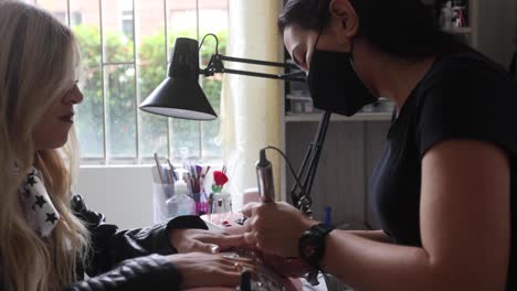 anonymous master polishing nails of female customer with electric file