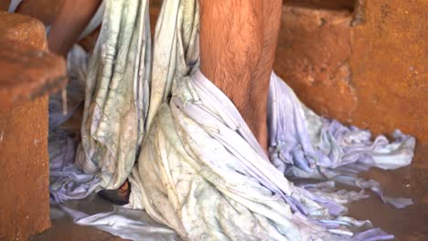 A-man-with-peaces-of-leather-around-the-legs-in-a-tannery-in-Fez,-Morocco