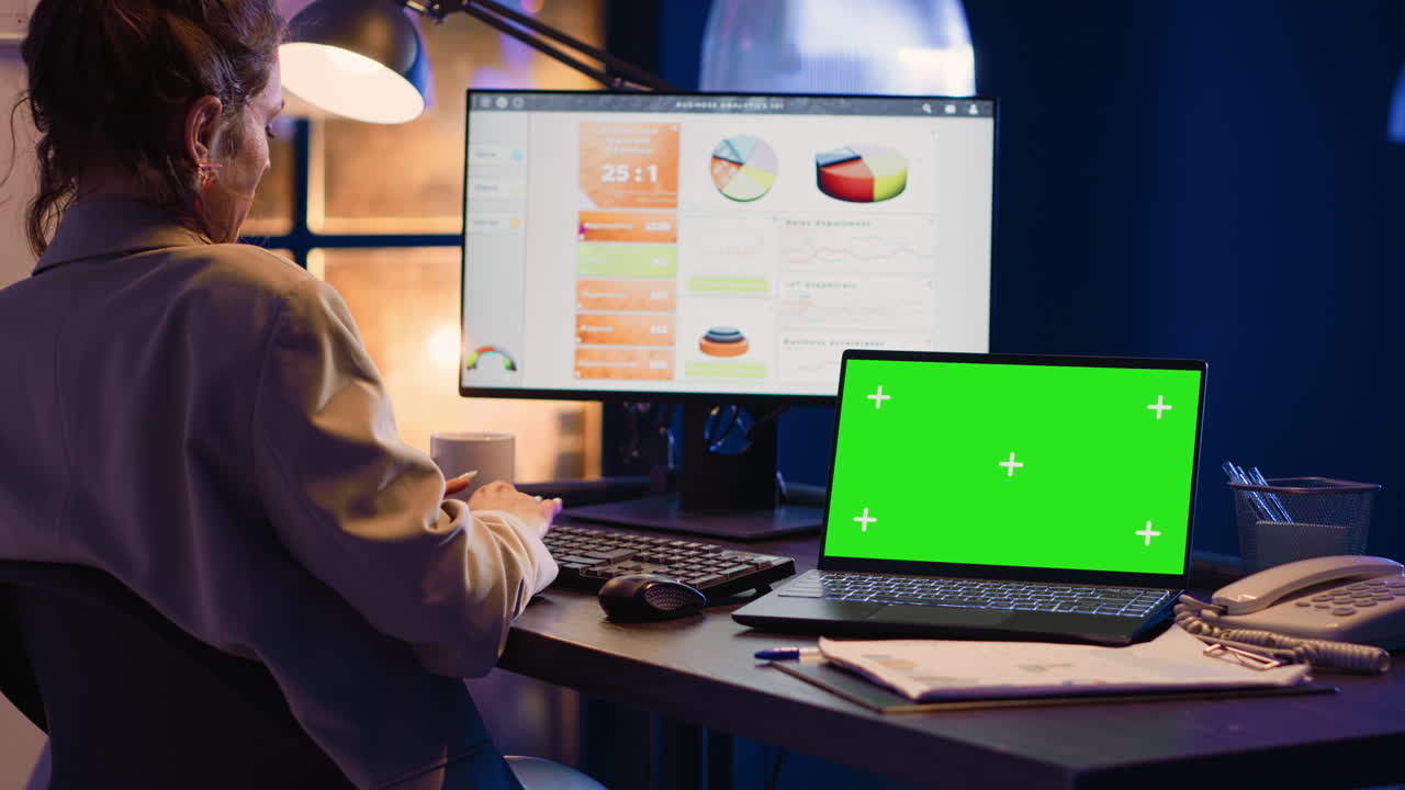 Woman working on laptop with chroma key screen in office