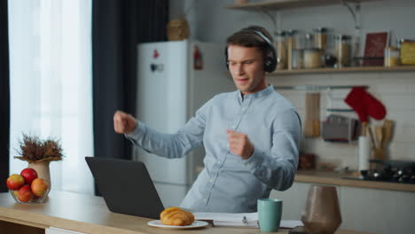 melomaniac disfruta de auriculares de música con portátil en la cocina. dj trabajando desde casa.