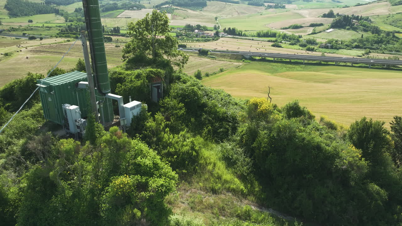 울창한 초록색과 굴곡된 언덕으로 둘러싸인 버려진 통신 타워, 공중 사진