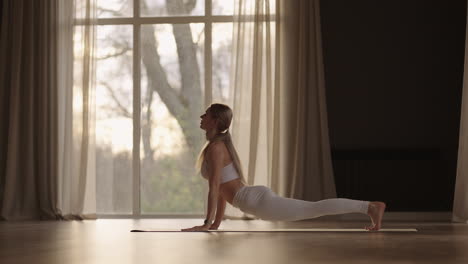 A-young-woman-exercises-performing-exercises-from-yoga-in-slow-motion-in-sunlight.-Light-through-the-window-sunlight