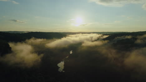 Aerial-drone-shot-slowly-rising-up-out-of-fog-filled-forest-river-valley,-4K