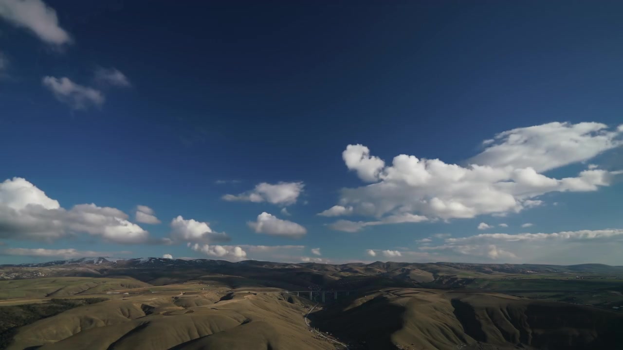 Time-lapse aereo di nuvole che si muovono su colline ondulate e una valle