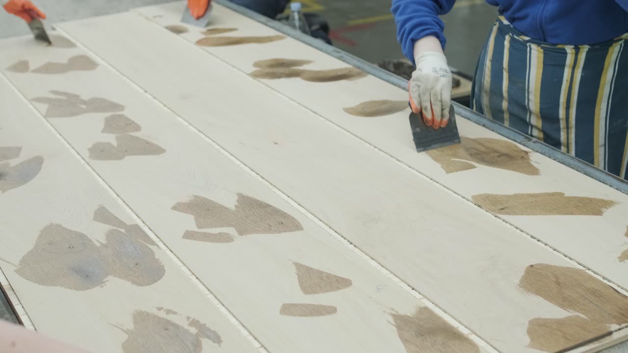 Operai che applicano stucco su listoni di legno in fabbrica