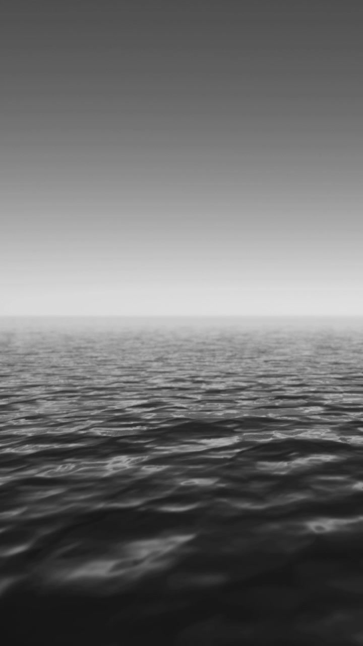 Wide view of calm sea under clear sky at dawn with soft waves and horizon