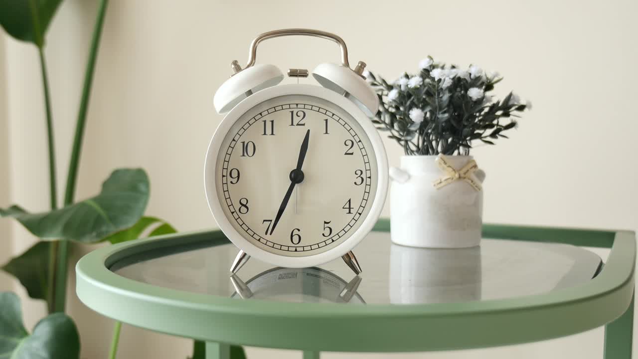 White Alarm Clock Ticking on a Green Side Table