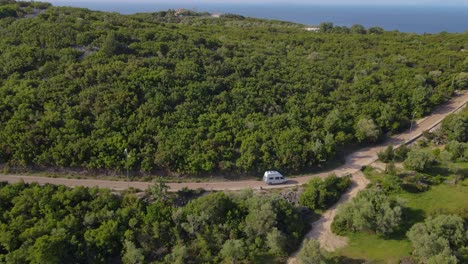 A-van-moving-on-the-track-of-the-coastline-of-the-ocean,-Captured-by-drone,-Albania