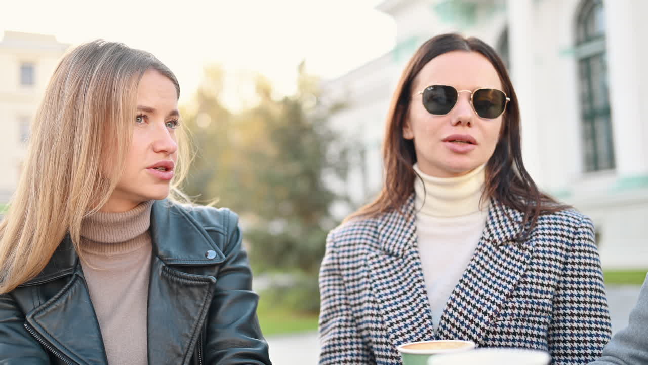 Two women talking and drinking coffee at a terrace