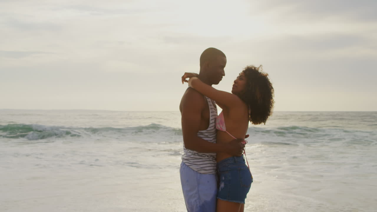 vista lateral de una pareja afroamericana bailando juntos en la playa 4k