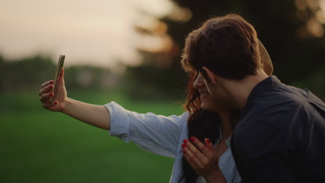 Yonug-couple-having-video-chat-online-on-mobile-phone-at-meadow