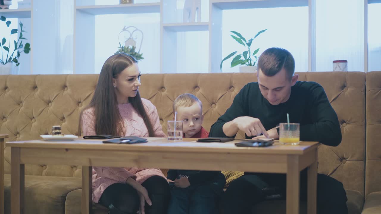 una mujer bonita habla con un niño con un suéter rojo en un restaurante