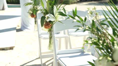 slow panning shot of wedding venue chairs in the aisle with flowers on top of each chair