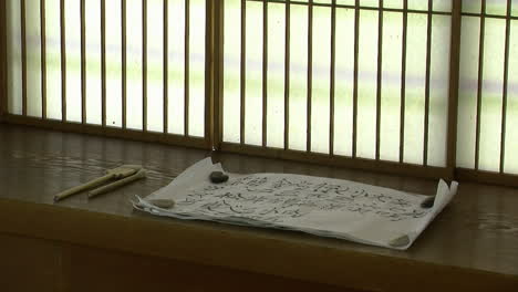 scroll of calligraphy sits on a shoin desk in a japanese house