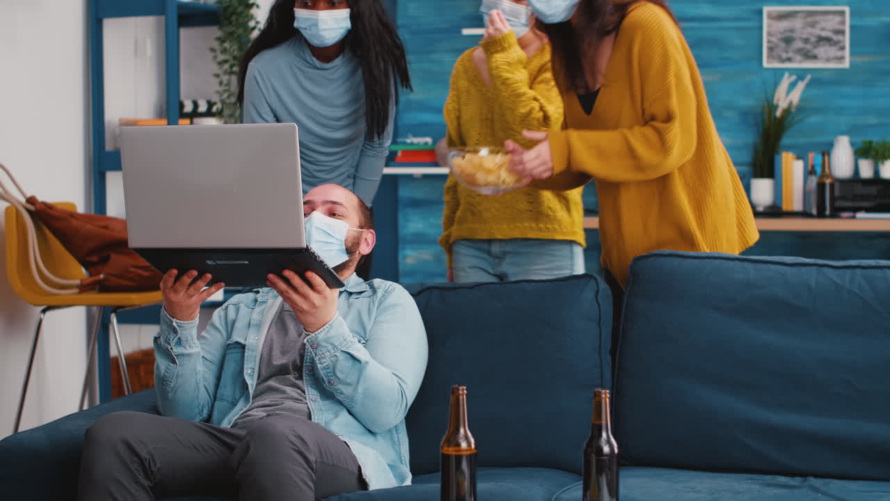 Multiracial friends browsing using laptop keeping social distancing