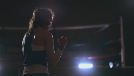 una hermosa mujer lleva a cabo una lucha de sombras mientras practica duro para futuras victorias. fondo de gimnasio oscuro. toma de steadicam