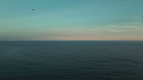aerial view of deep blue sea with small plane passing by