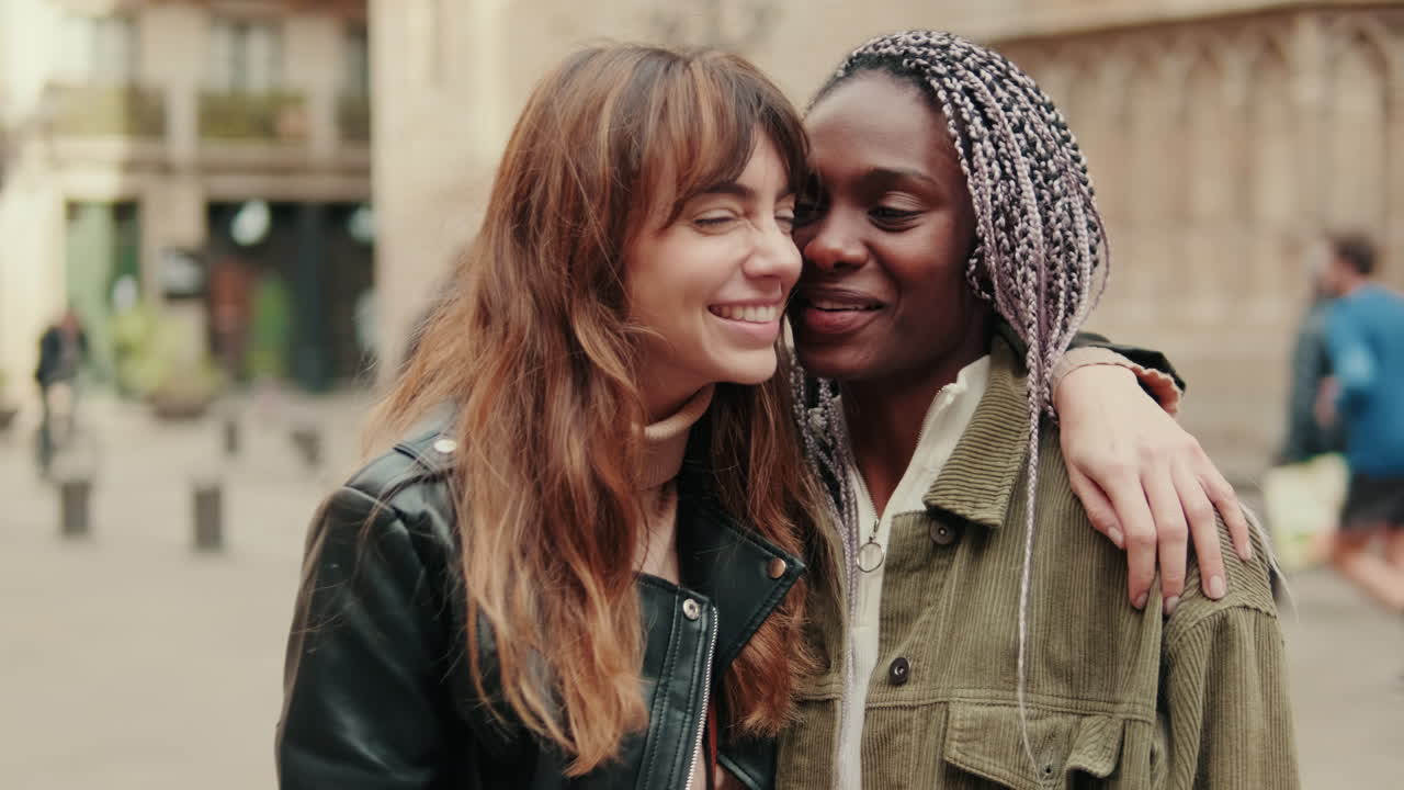 Mulheres multiétnicas alegres abraçando-se e sorrindo em um ambiente urbano.