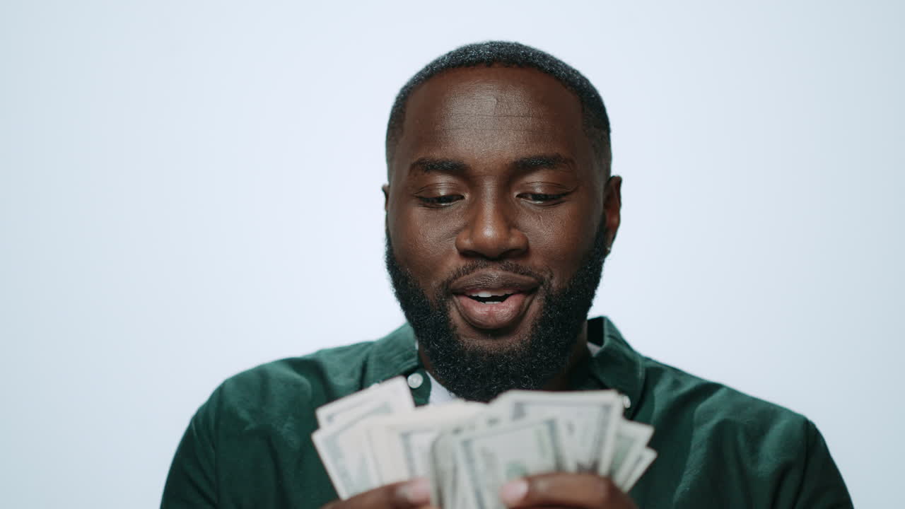 Portrait of happy african american man counting money on grey background.