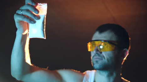 a gangster is examining the quality of the white powder in the basement. close-up. illegal narcotics production. drug trafficking