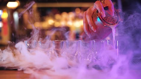 bartender filling up shot glasses with alcoholic drinks