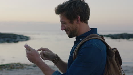 retrato de un hombre caucásico en la playa usando un teléfono tomando una foto del hermoso océano costero