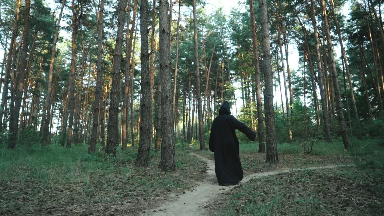 Halloween Horror Man with Black Cape Walking in Forest