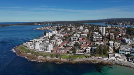 Aerial of Cronulla peninsula with dramatic rocky edge and homes by the coastline, establishing overview, Sydney NSW Australia