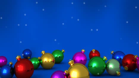 Animation-of-snow-falling-over-christmas-bauble-decorations-on-blue-background