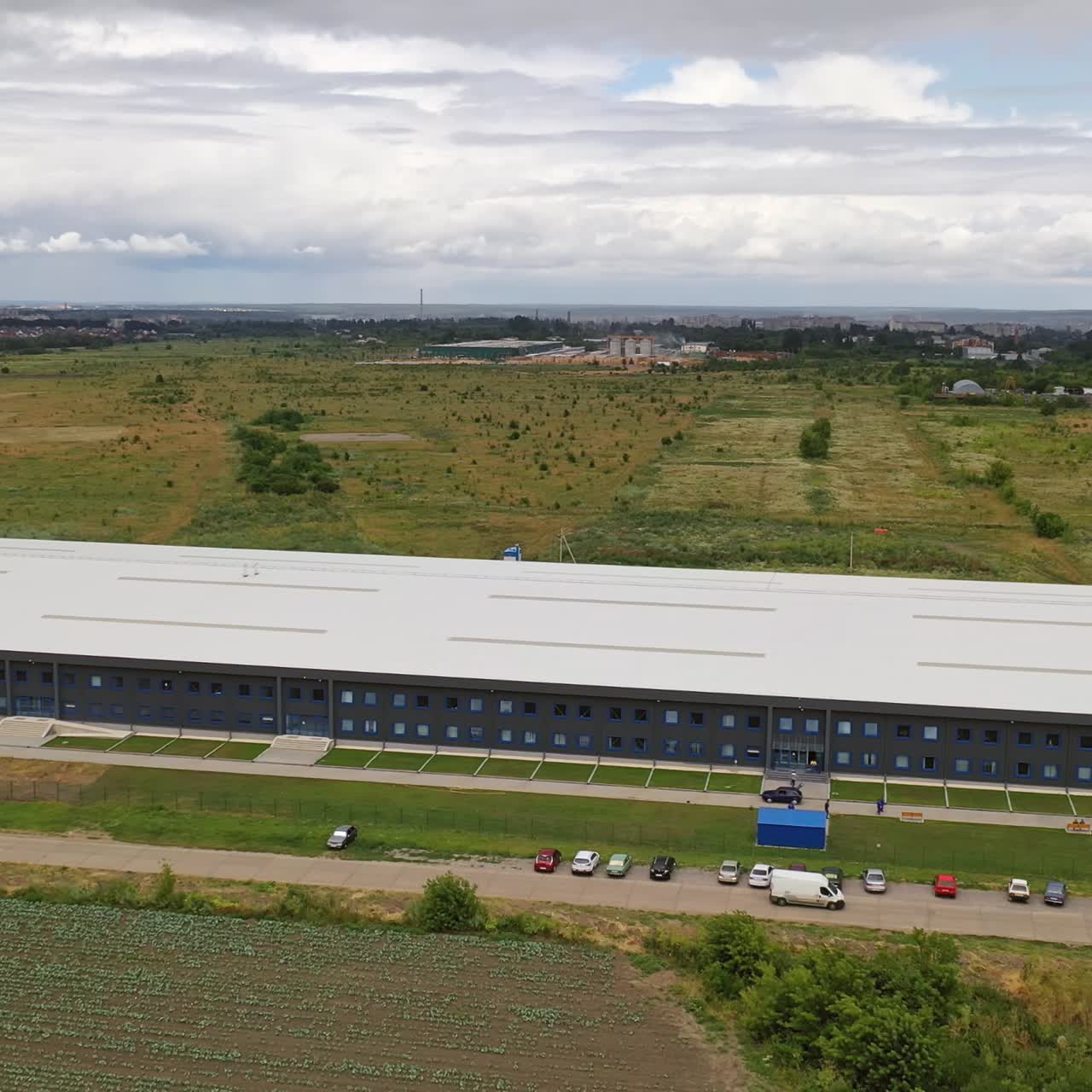 Aerial view of a modern industrial warehouse or logistics center in a vast rural landscape