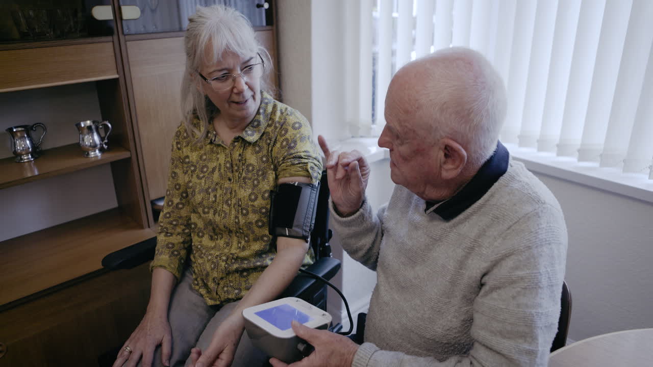 An elderly man has his blood pressure checked by a caregiver