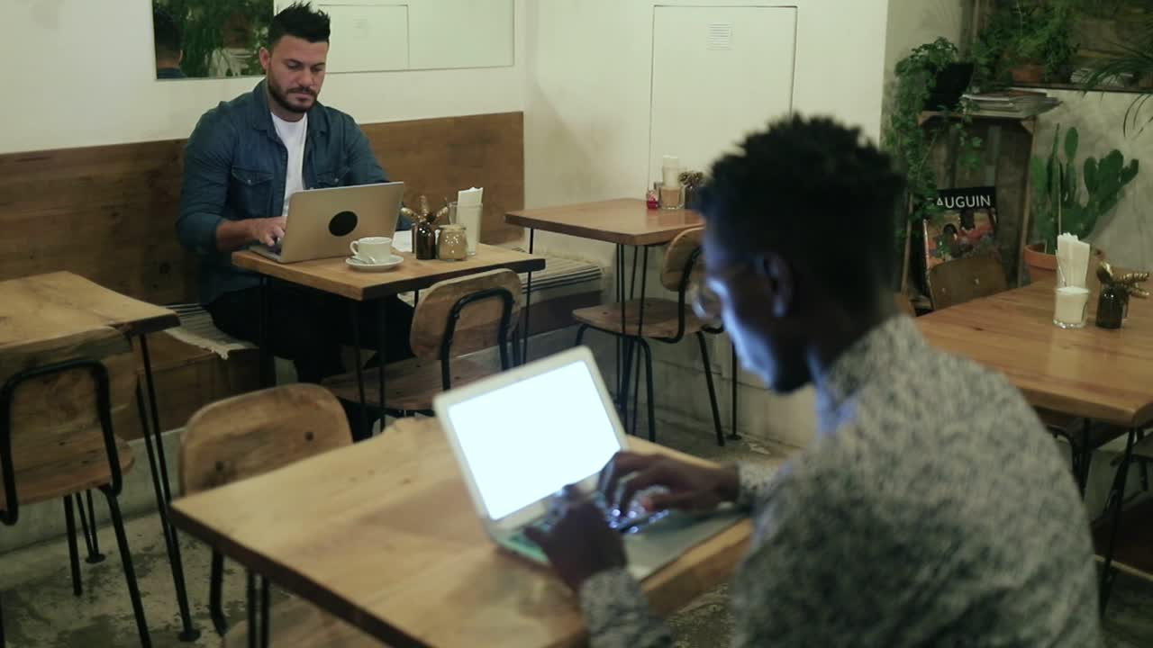 freelancers multirraciales trabajando con computadoras portátiles en un café