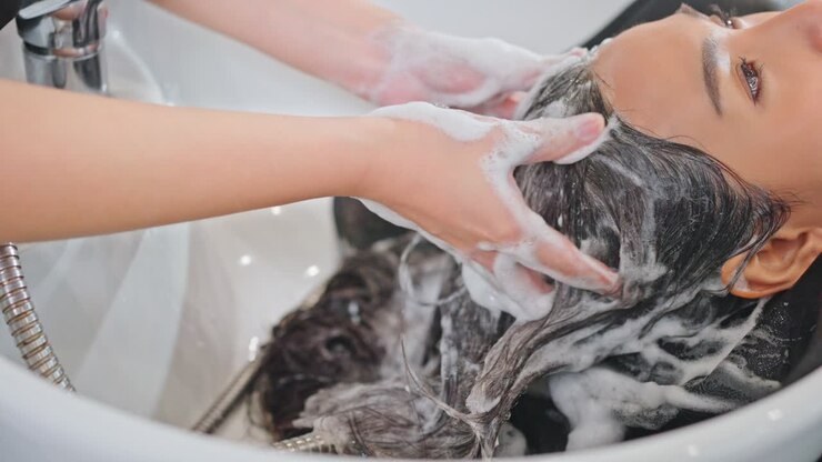 uma mulher a lavar o cabelo num salão de beleza.