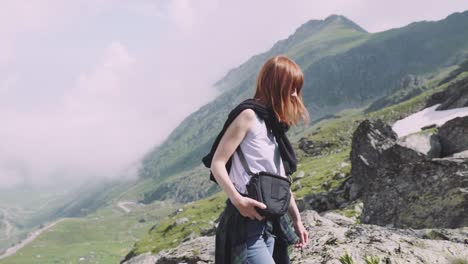 a young woman hiker climbs mountains with photo camera. transfagarasan, carpathian mountains in romania