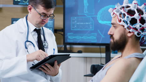 paciente sentado en una cama de hospital y usando auriculares de escaneo de ondas cerebrales