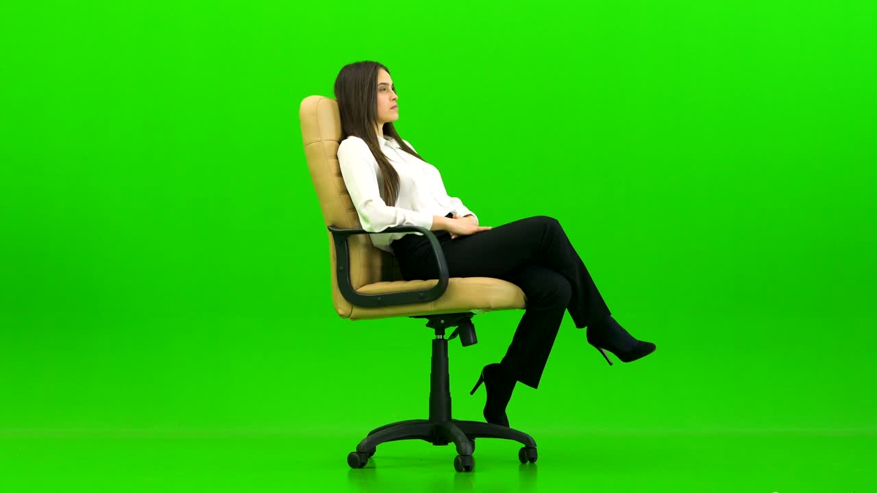 초록색 배경에 사무실 의자를 돌리는 여자