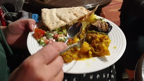 Close-up-of-person-eating-a-plate-of-delicious-traditional-Jordanian-food-with-flat-bread-on-their-travels-in-Jordan,-Middle-East