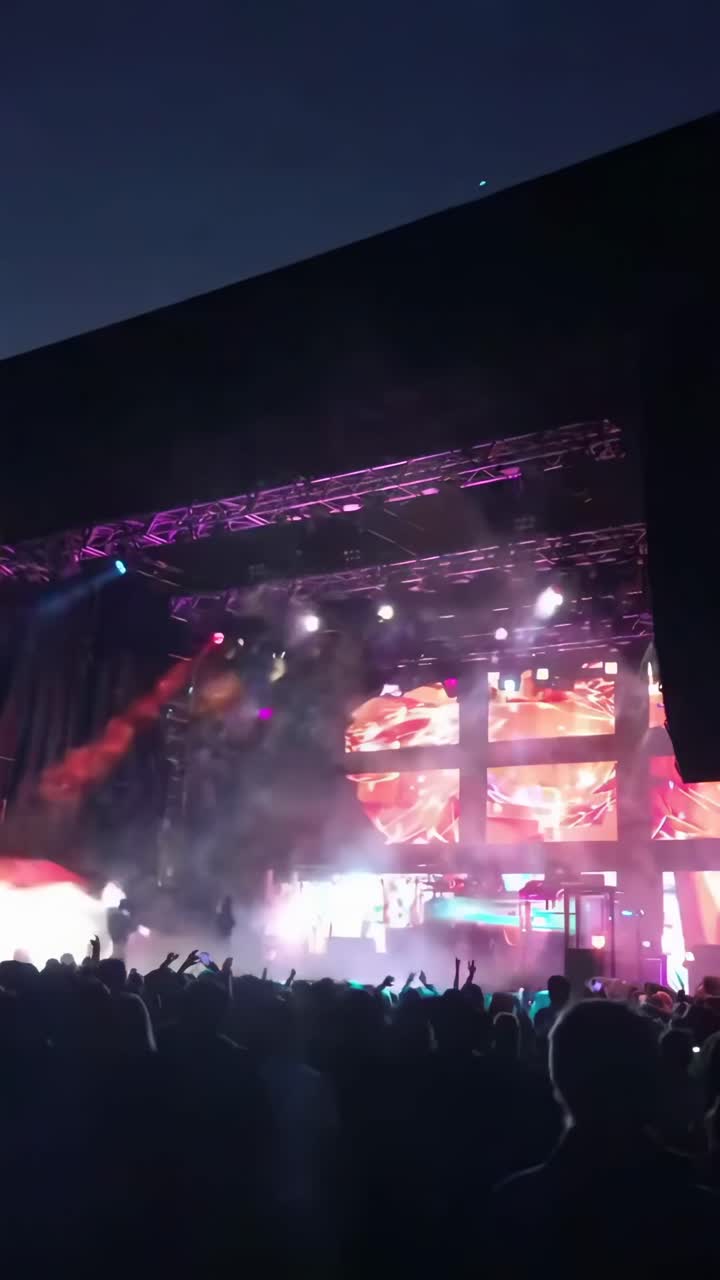 Video vibrante di un concerto ripreso dal basso, che cattura luci di scena colorate e artisti energici.