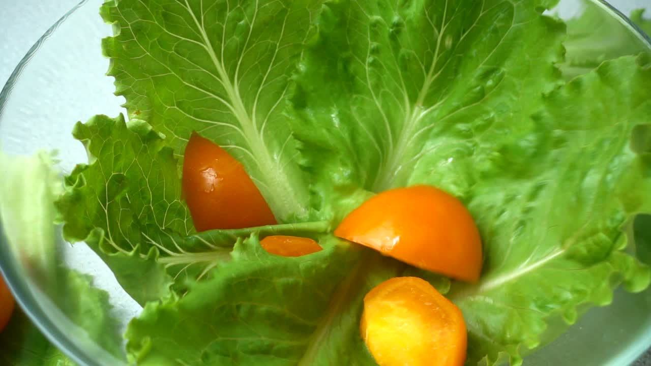 The falling tomatoes on lettuce leaves. Slow motion