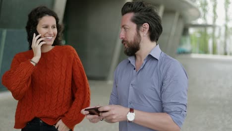 hombre y mujer usando teléfonos celulares al aire libre