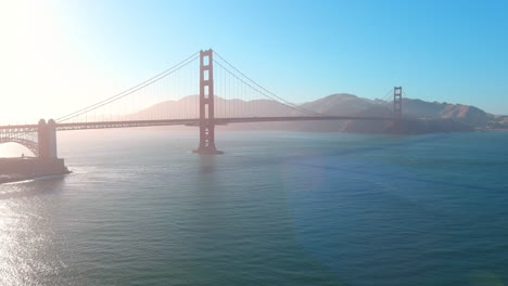 cinematic pan right of the golden gate bridge at sunset, with soft haze over san francisco bay and view toward marin
