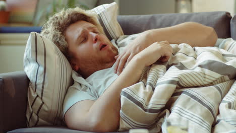 sick man lying on sofa and coughing