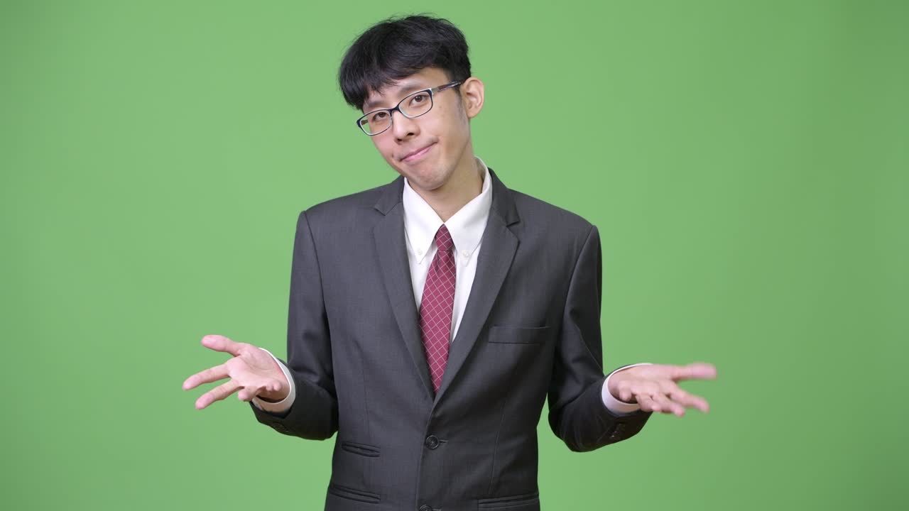 Young confused Asian businessman shrugging shoulders