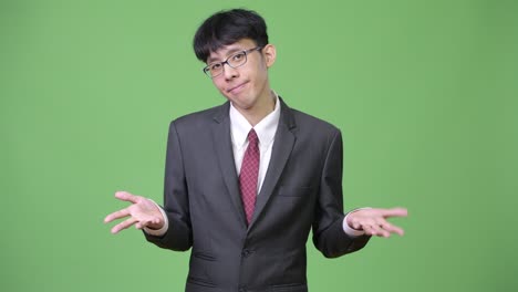 young confused asian businessman shrugging shoulders