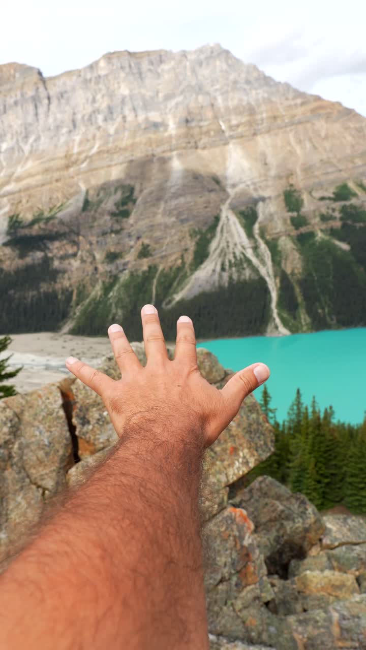 Una mano tesa verso un lago panoramico e un paesaggio montano