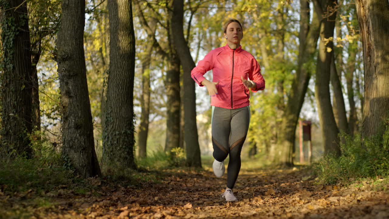 Donna che corre su un sentiero attraverso un parco autunnale