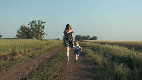 Happy-mother-and-daughter-walking-together-outside-on-country,-dirt-road-on-a-farm-in-summer-sunset-having-positive,-loving-family-or-mothers-day-moment-in-cinematic-slow-motion